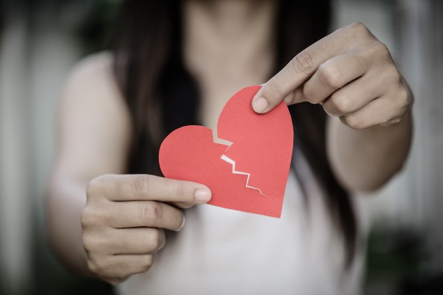 Young woman showing red ripped paper heart. Broken hearted on Valentines day concept.